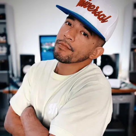 Bboy Wicket in a cap, arms crossed, in a studio
