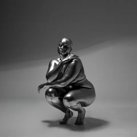 LATASHÁ’s artist image: a silver figure crouching