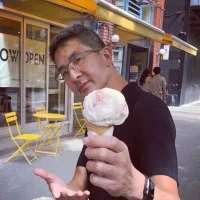 C.Y. Lee holding up an ice cream cone on a sidewalk